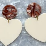 Close up of Acrylic Heart Earrings in Bare My Love and cream 