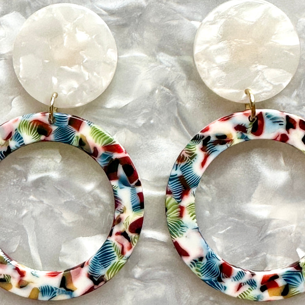 woman wearing Acrylic open circle drop earrings in red, blue. green and white