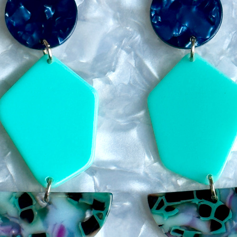 Close up of Acyrlic Pendulum Drop Earrings in Along For The Vibe, navy blue and teal green 