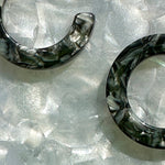 Close up of mini acrylic hoop earrings in a mix of black, gray, and white 