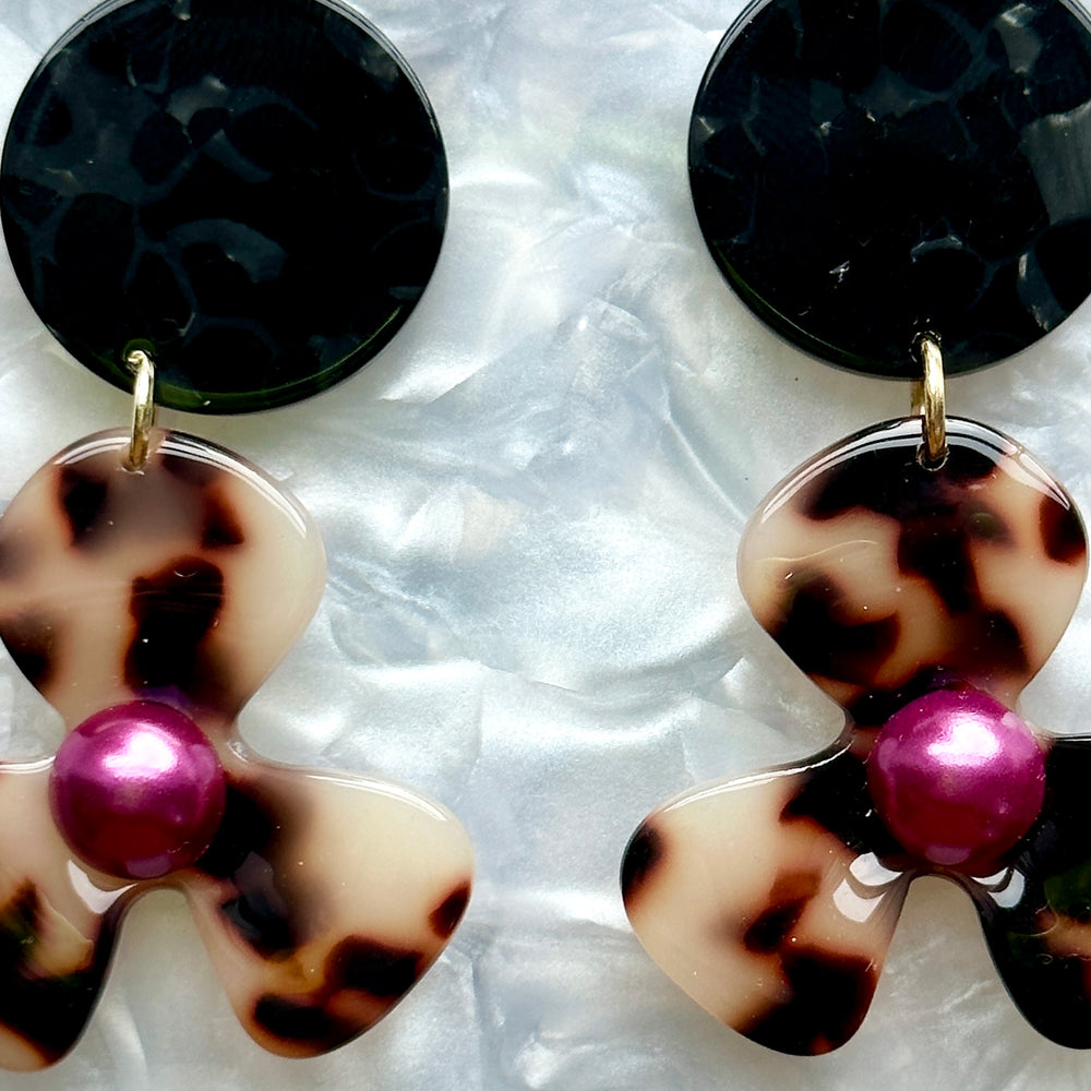 close up of Acrylic Flower Drop Earrings in black, purple, and beige