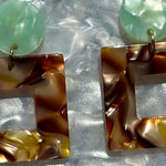 close up of Acrylic Square Drop Earrings in Peanut Brittle, brown, lod and teal green 