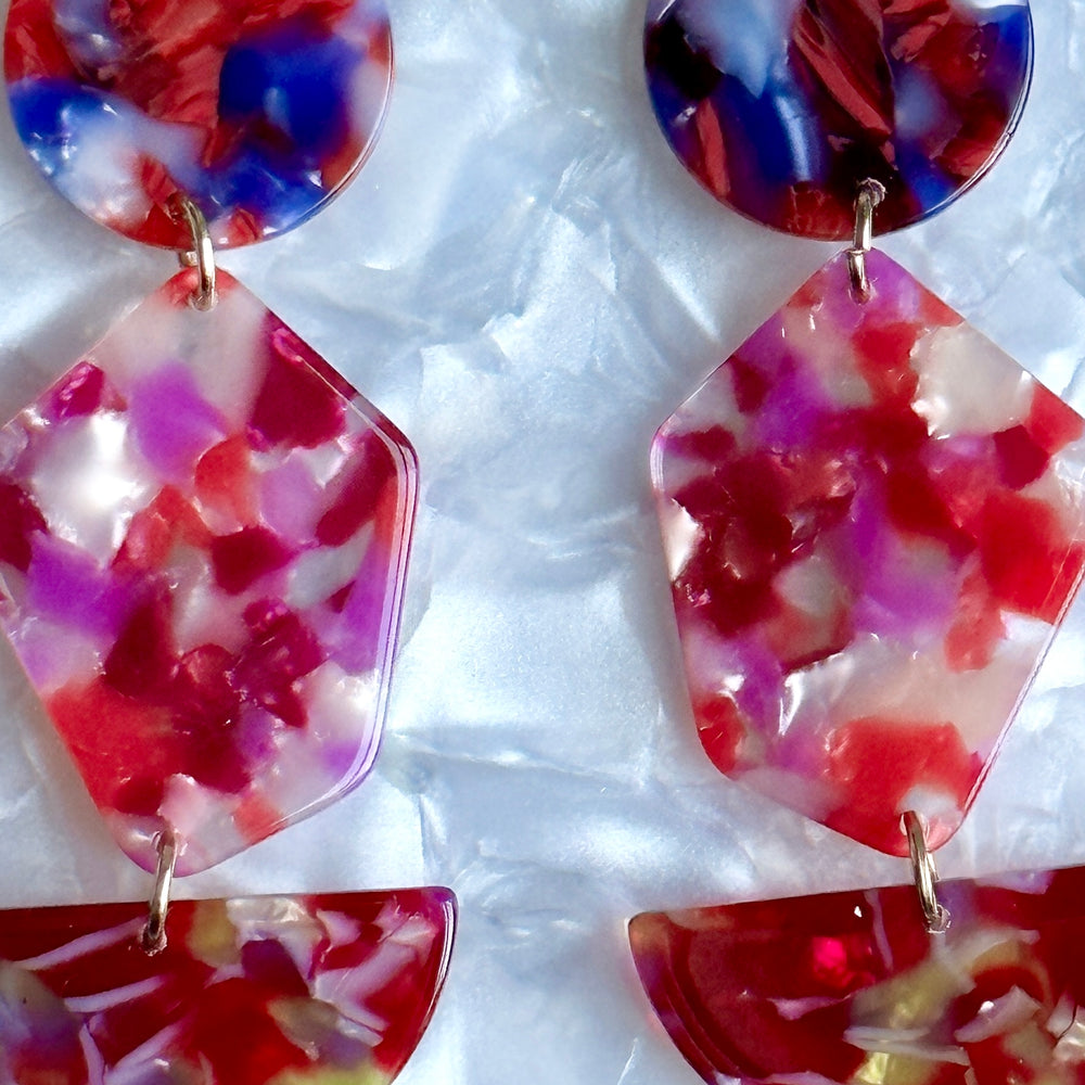 close up of acrylic Pendulum Drop Earrings in Fuchsia Is Bright, red, pink, purple, and yellow 