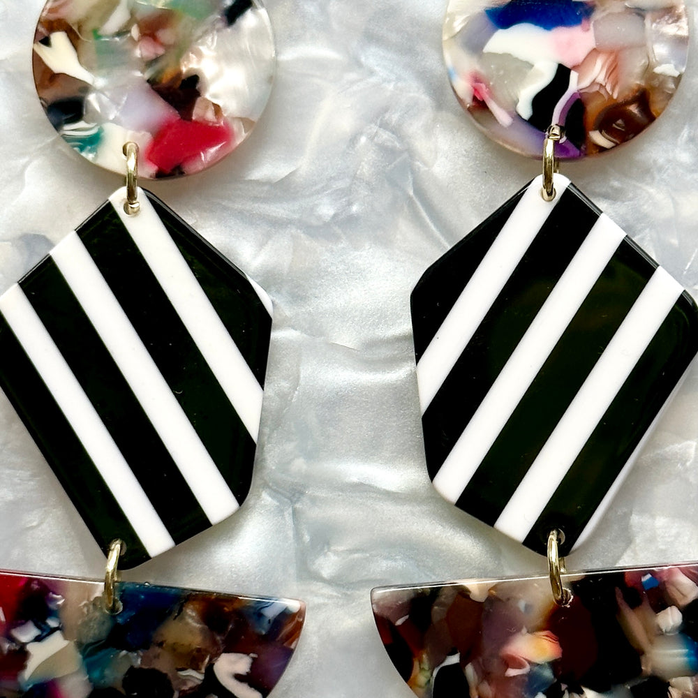 woman wearing a acrylic Pendulum Drop Earrings in black, white, light and dark multicolor