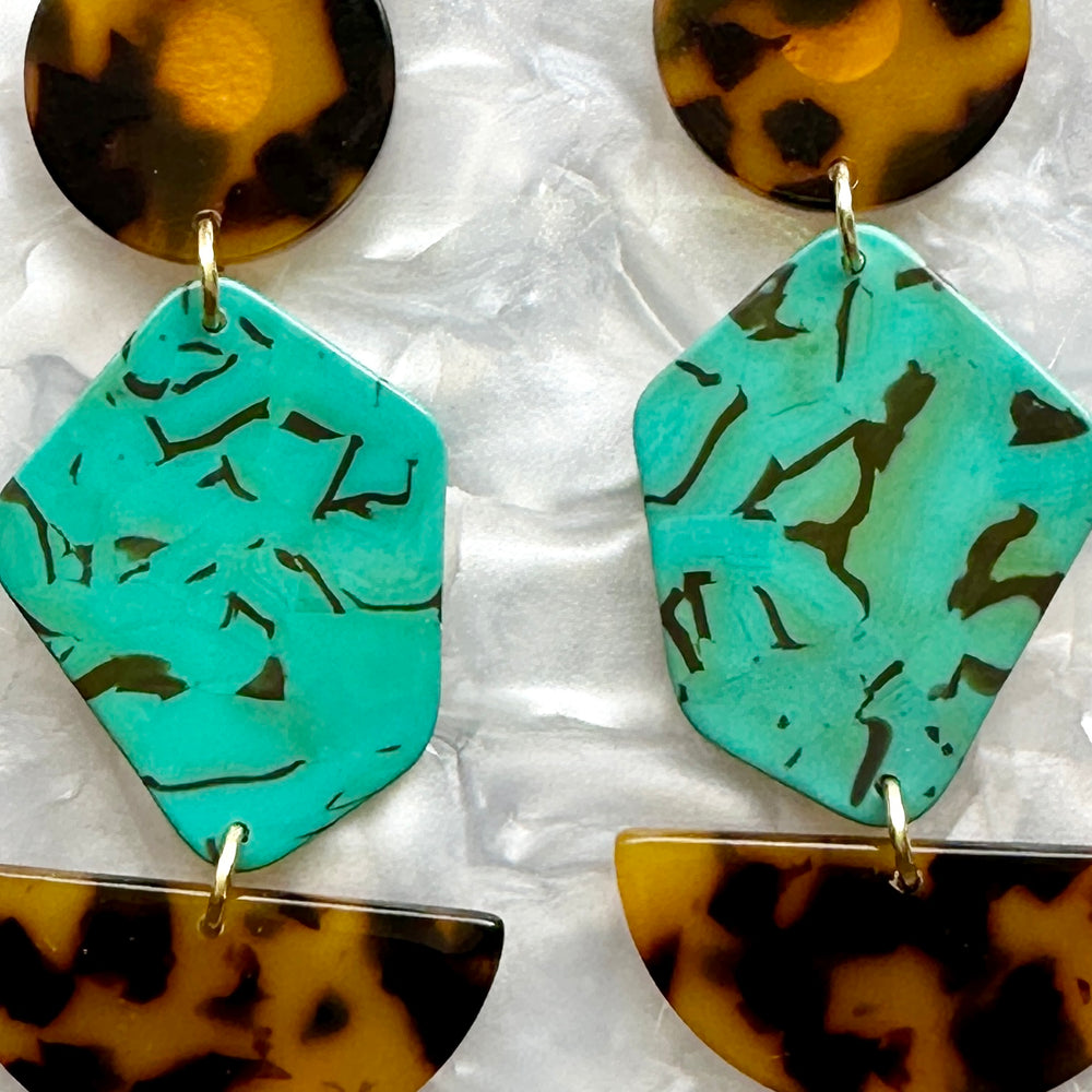 close up of acrylic Pendulum Drop Earrings in brown, black, teal green