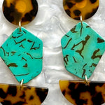 close up of acrylic Pendulum Drop Earrings in brown, black, teal green