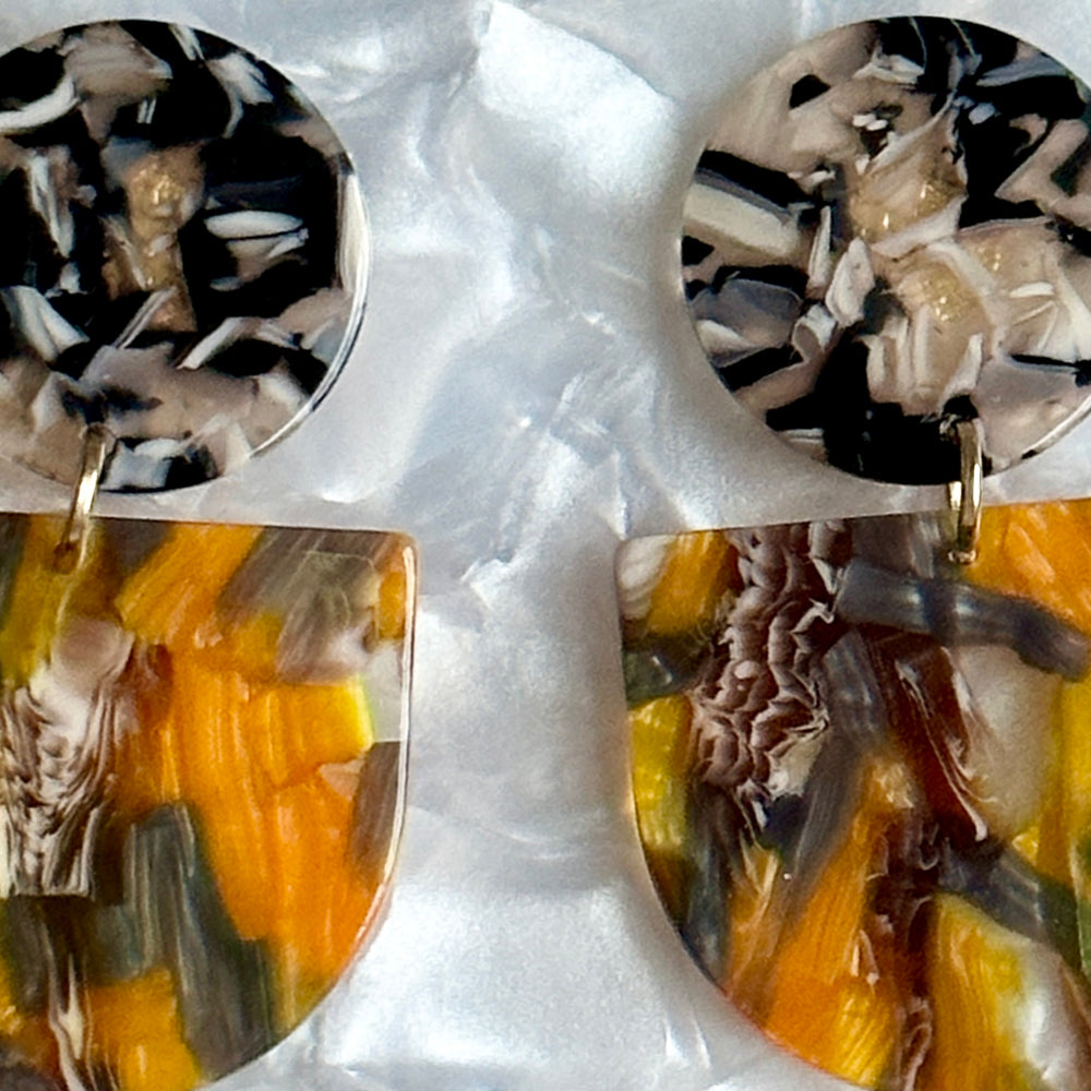 close up of acrylic Tab Drop Earrings in orange, black and gray