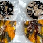 close up of acrylic Tab Drop Earrings in orange, black and gray