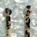 close up of acrylic matchstick earrings in black and white tortoise