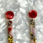 close up of acrylic matchstick earrings in lilac, red and yellow