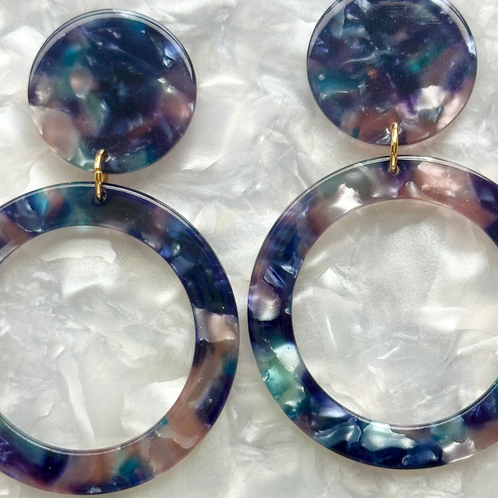 woman wearing acrylic open circle drop earring in a deep blue, light pink and purple 