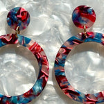 woman wearing acrylic open circle drop earring in blue and dark pink 