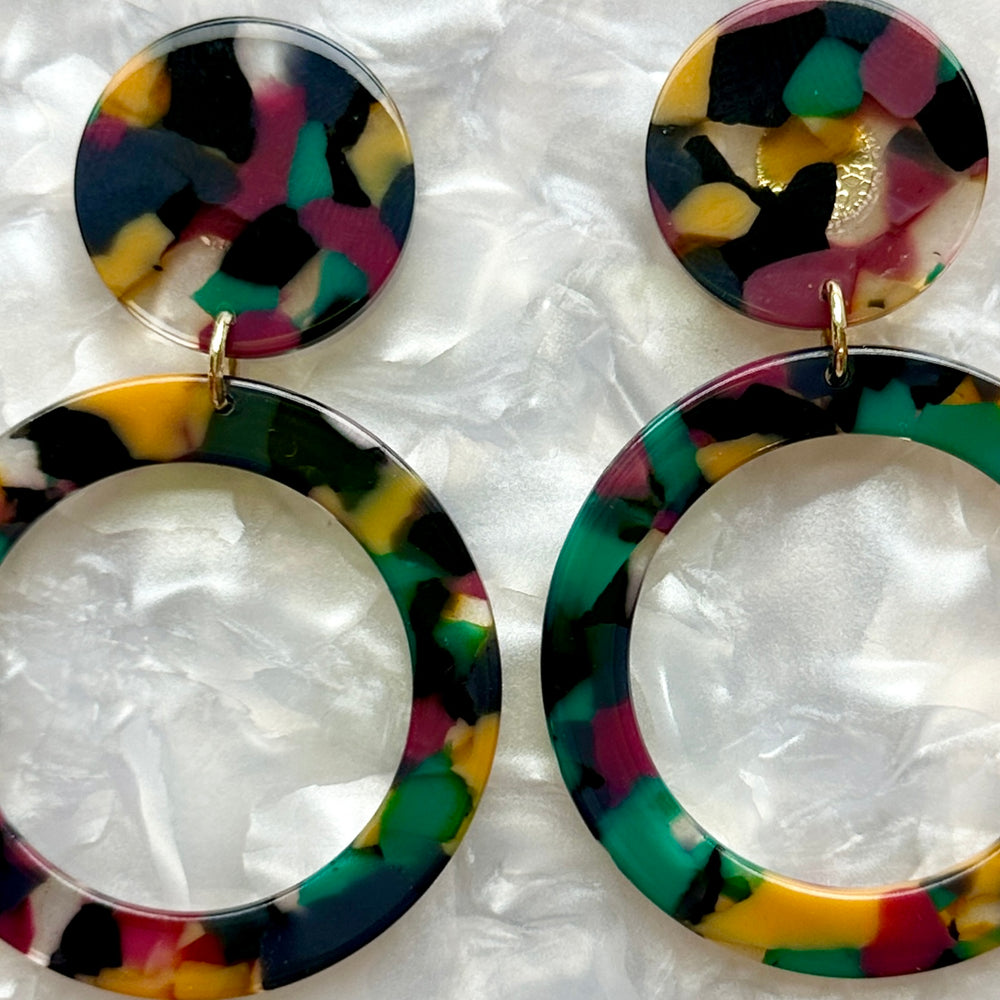 close up of acrylic open circle drop earring in dark red, green, yellow, and Black 