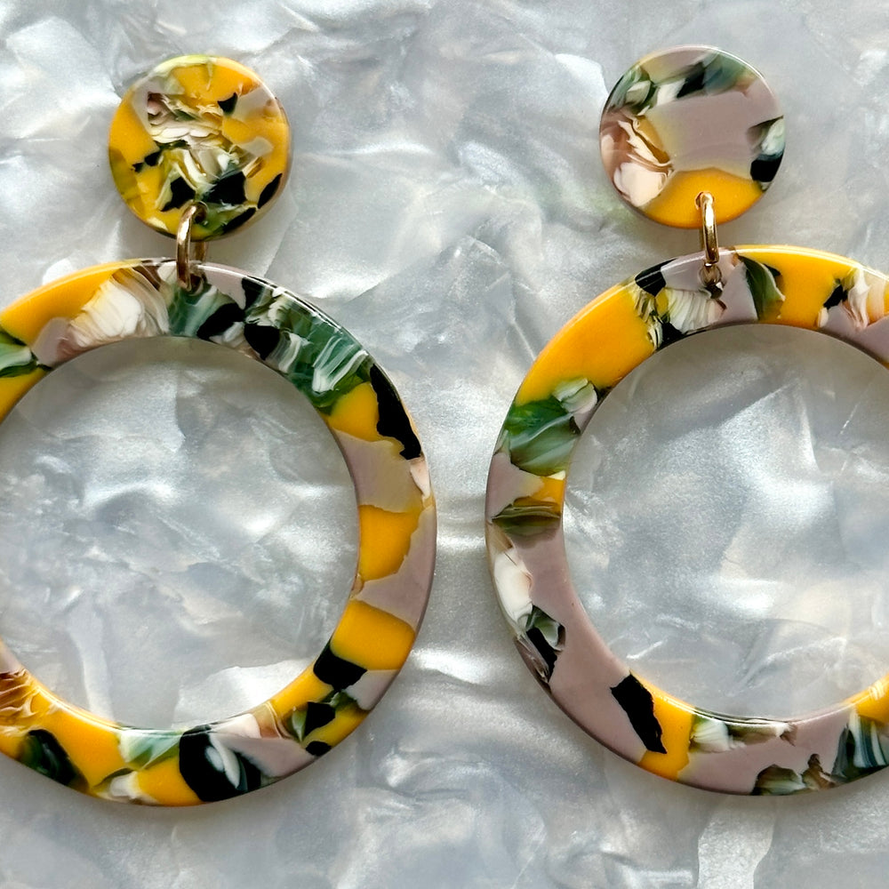 woman wearing acrylic open circle drop earring in yellow, green and gray 