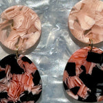 woman wearing a acrylic organic circle drop earring in black and pink 