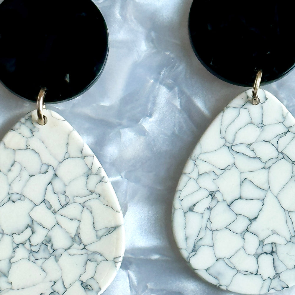 close up of acrylic teardrop earrings in white, gray, and black 