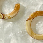 close up of mini acrylic hoop earrings in yellow and cream 