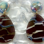 close up of mini acrylic teardrop earrings in gray and iridescent 