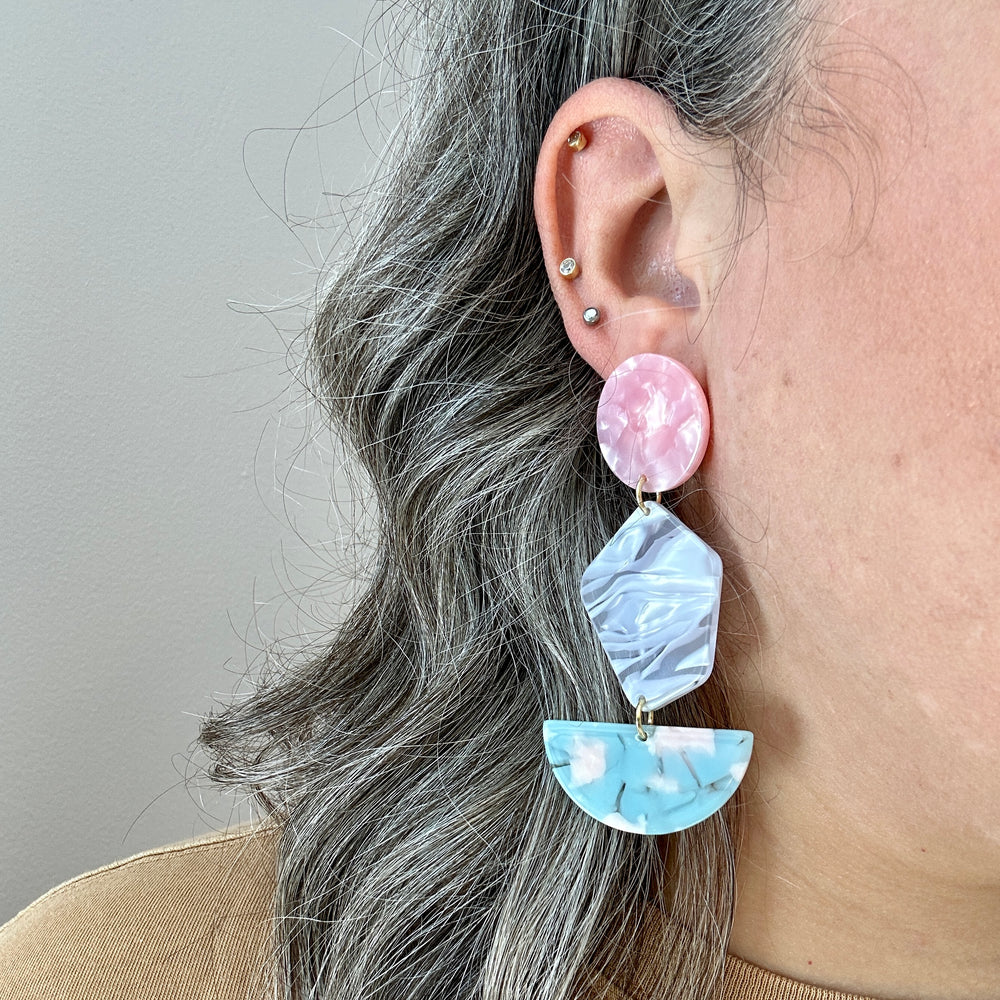 woman wearing Acrylic Pendulum Drop Earrings in Lover, pink, gray, and light blue 