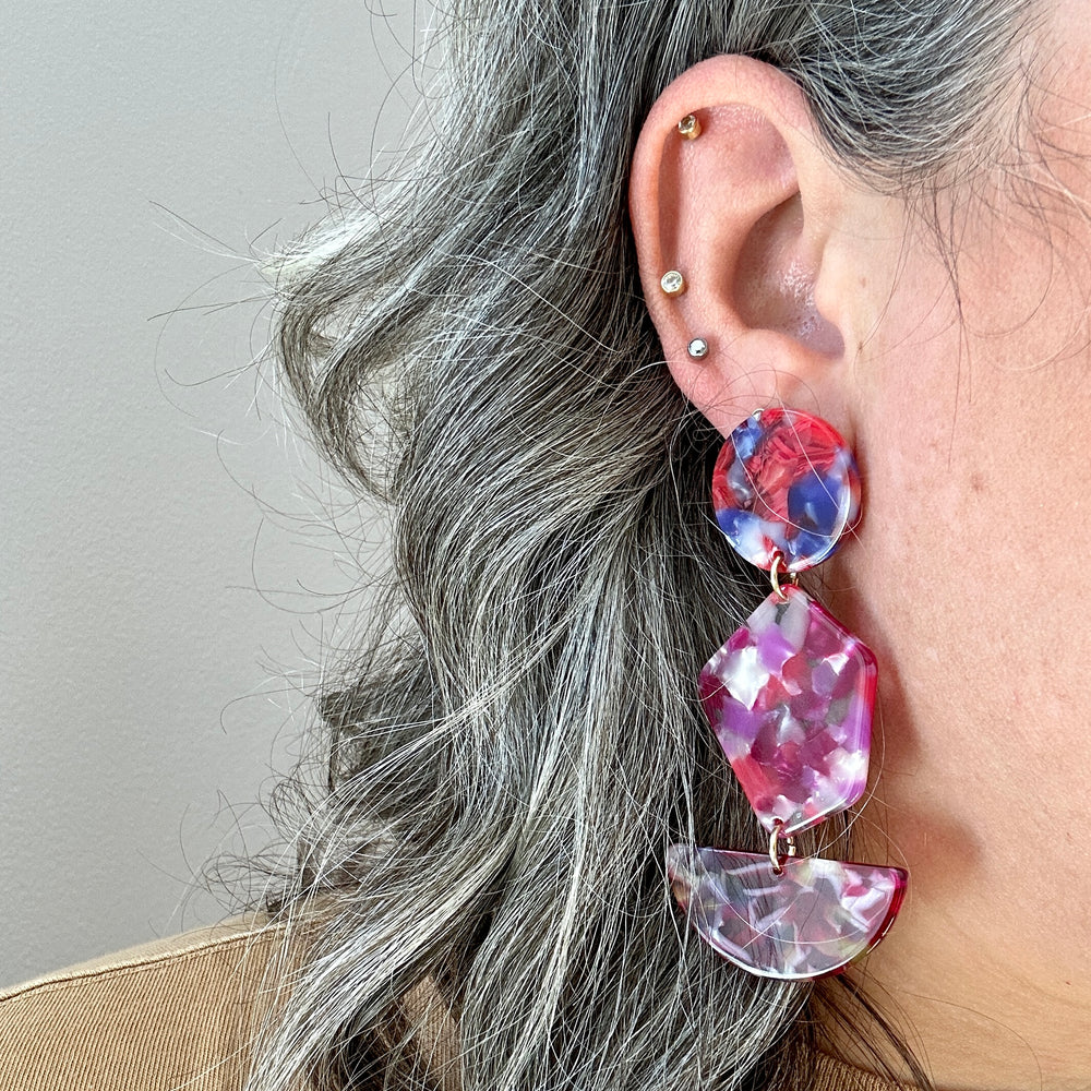 woman wearing acrylic Pendulum Drop Earrings in Fuchsia Is Bright, red, pink, purple, and yellow 