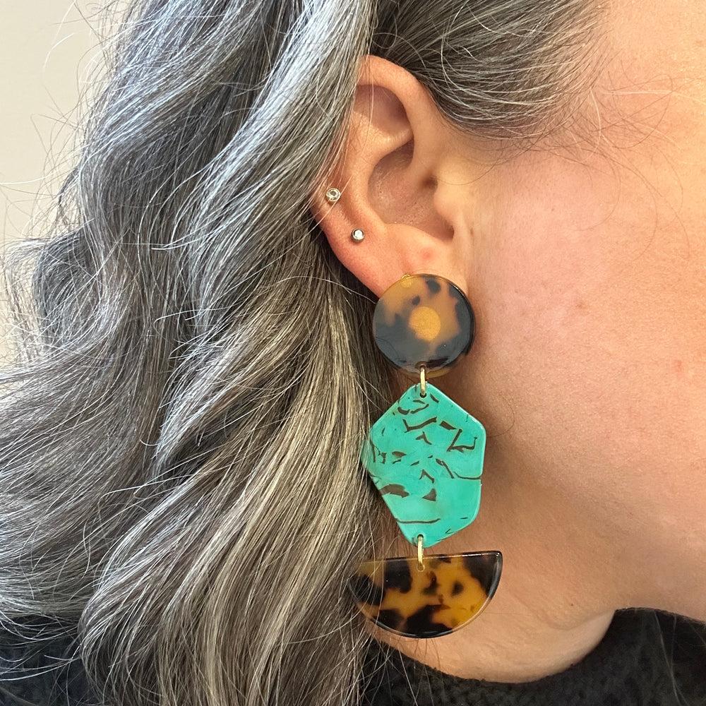 woman wearing acrylic Pendulum Drop Earrings in brown, black, teal green