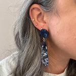 woman wearing acrylic flower Petal Drop Earrings in navy blue