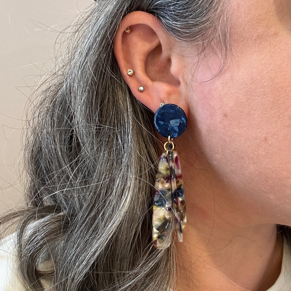 woman wearing acrylic flower Petal Drop Earrings in navy, green, white and magenta