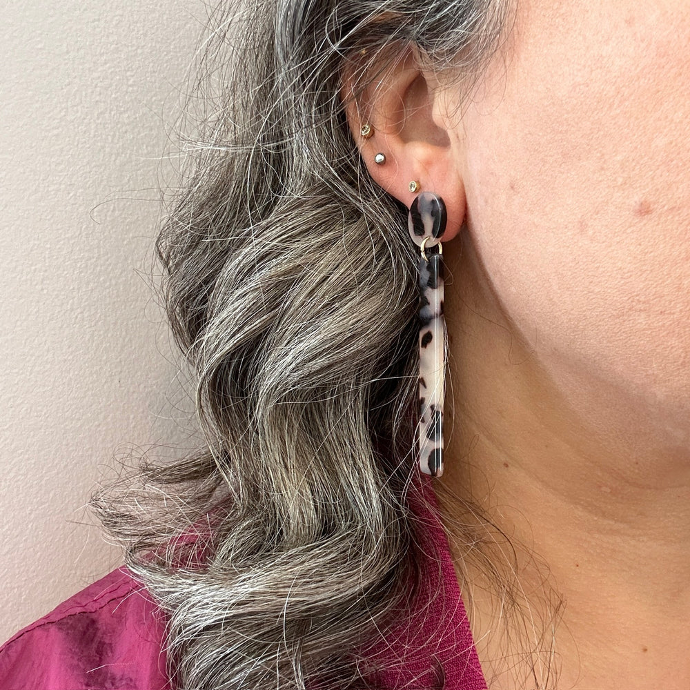 woman wearing acrylic matchstick earrings in black and white tortoise