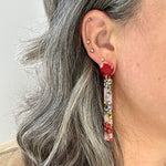 woman wearing acrylic matchstick earrings in lilac, red and yellow