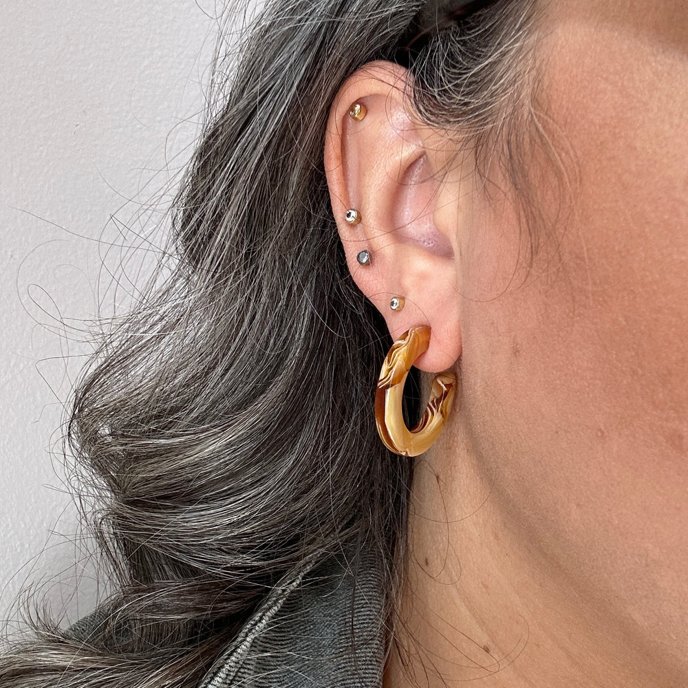 woman wearing mini acrylic hoop earrings in yellow and cream 