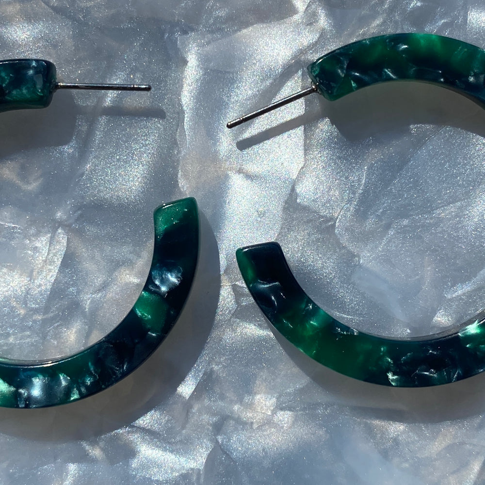 close up of  acrylic hoop earrings in dark green and navy