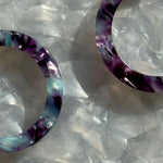 woman wearing acrylic hoop earrings in purple and blue 