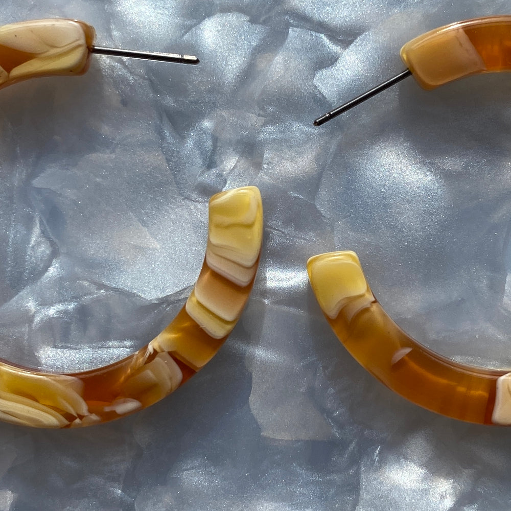 woman wearing acrylic hoop earrings in yellow and cream