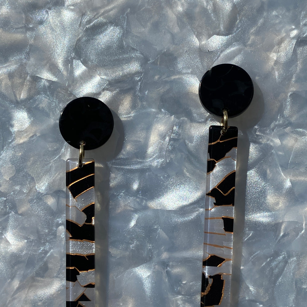 close up of acrylic matchstick earrings in black and white crackle