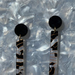 woman wearing acrylic matchstick earrings in black and white crackle