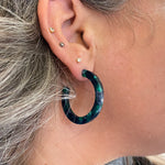 woman wearing  acrylic hoop earrings in dark green and navy