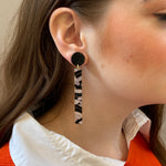 woman wearing acrylic matchstick earrings in black and white crackle